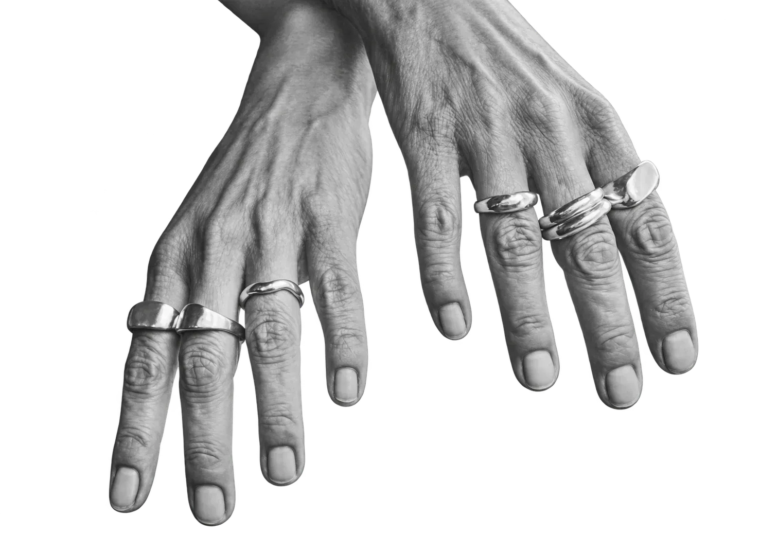 Händer med flera handgjorda silverringar.